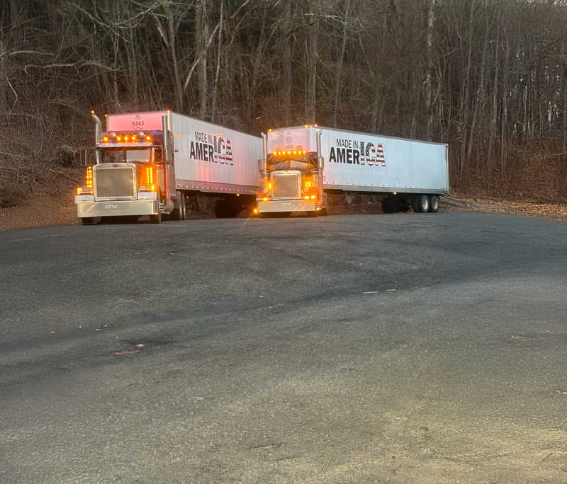 Two trucks with 'AMERICA' branding on a road at night.